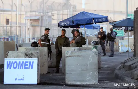 Israeli soldiers wait for Palestinian men and women to arrive at the Qalandia checkpoint, to cross into Jerusalem to take part in the Friday noon prayers at the Al-Aqsa mosque compound, on the second Friday of the holy M...
