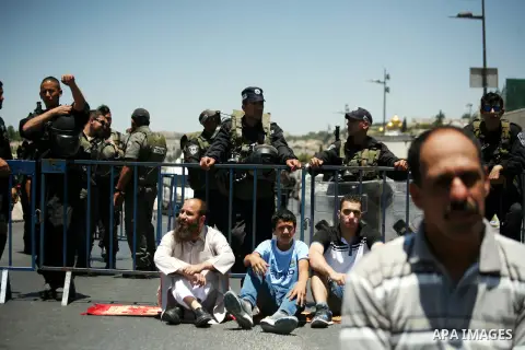 Palestinians pray as Israeli policemen stand guard during prayers on the second Friday of the holy fasting month of Ramadan in the Arab East Jerusalem neighbourhood of Ras al-Amud July 11, 2014. Israeli police on Friday...