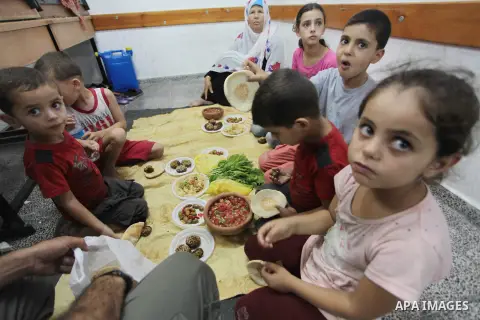 A Palestinian family breaks its day-long fast at a UN school in Gaza City on July 13, 2014, after evacuating its home near the border with Israel. Israel harshened its campaign against Gaza, warning Palestinians in the n...