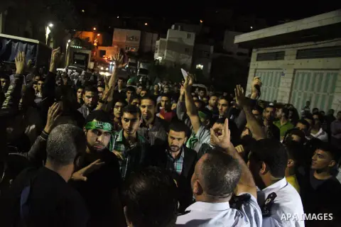 Palestinian policemen stand in front of Hamas supporters during a demonstration against Israeli military operations in the Gaza strip, in the West Bank City of Hebron July 15, 2014. Israel resumed its heavy bombardment o...