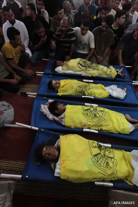 Palestinians mourn over the body of boys from the Baker family, whom medics said was killed by a shell fired by an Israeli naval gunboat, in Gaza city on July 16, 2014. Four Palestinian children were killed and one was c...