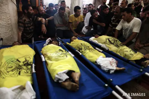 Palestinians mourn over the body of boys from the Baker family, whom medics said was killed with three other children from the same family by a shell fired by an Israeli naval gunboat, in Gaza city on July 16, 2014. Four...