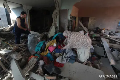 Palestinians carry their belongings as they walks past debris after which police said was targeted in an Israeli air strike in Gaza City July 17, 2014. Israeli shelling killed four Palestinian boys on a Gaza beach on Wed...