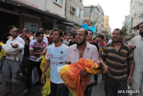 Palestinian relatives shout as they carry the bodies of kids during the funeral of eight members of Abu Jarad family who were killed overnight in an Israeli strike on July 19, 2014 in Beit Lahia, north of the Gaza strip....