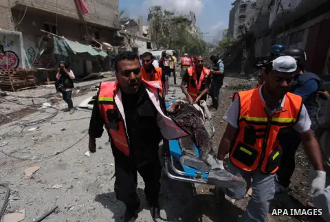 Medics evacuate the body of a man from Gaza's eastern Shejaiya district on July 20, 2014. At least 60 people were killed and nearly 400 wounded in Israeli shelling of Gaza's northeastern Shejaiya district overnight, medi...