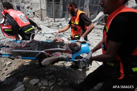Medics evacuate the body of a man from Gaza's eastern Shejaiya district on July 20, 2014. At least 60 people were killed and nearly 400 wounded in Israeli shelling of Gaza's northeastern Shejaiya district overnight, medi...