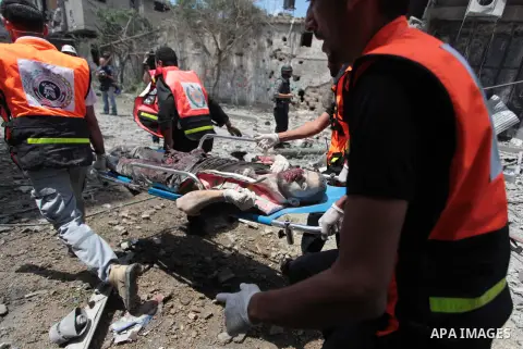 Medics evacuate the body of a man from Gaza's eastern Shejaiya district on July 20, 2014. At least 60 people were killed and nearly 400 wounded in Israeli shelling of Gaza's northeastern Shejaiya district overnight, medi...