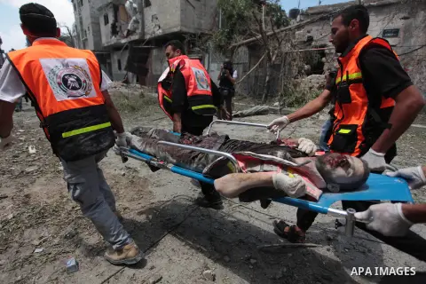 Medics evacuate the body of a man from Gaza's eastern Shejaiya district on July 20, 2014. At least 60 people were killed and nearly 400 wounded in Israeli shelling of Gaza's northeastern Shejaiya district overnight, medi...