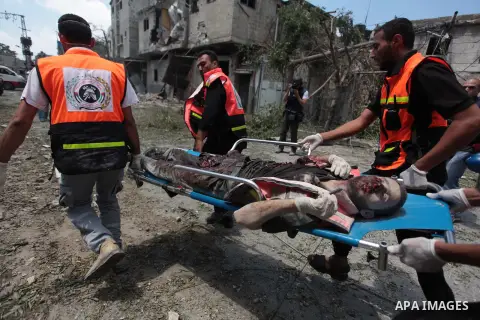 Medics evacuate the body of a man from Gaza's eastern Shejaiya district on July 20, 2014. At least 60 people were killed and nearly 400 wounded in Israeli shelling of Gaza's northeastern Shejaiya district overnight, medi...