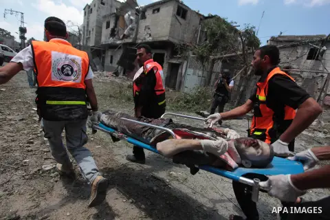 Medics evacuate the body of a man from Gaza's eastern Shejaiya district on July 20, 2014. At least 60 people were killed and nearly 400 wounded in Israeli shelling of Gaza's northeastern Shejaiya district overnight, medi...