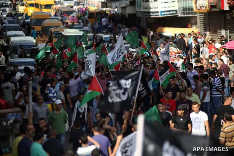 Palestinian protesters hold their national flags and signs during a demonstration against Israel's military action and violence in the Gaza strip, in West Bank City of Ramallah July 20, 2014. Israeli strikes on Gaza on S...