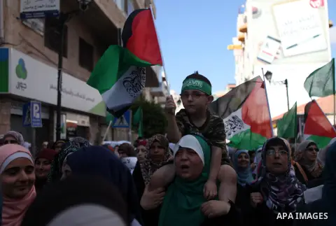 Palestinian protesters hold their national flags and signs during a demonstration against Israel's military action and violence in the Gaza strip, in West Bank City of Ramallah July 20, 2014. Israeli strikes on Gaza on S...