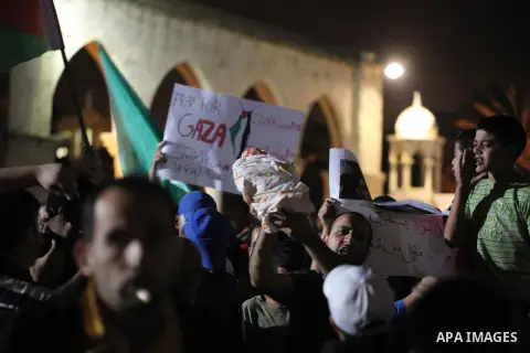 Palestinians hold a doll wrapped in a white cloth with red stains and shout slogans during a protest in front of the Dome of the Rock at the Al-Aqsa Mosque compound in the Old City of Jerusalem on July 20, 2014, in prote...