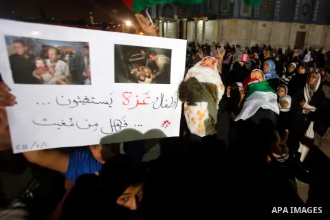 Palestinians hold a doll wrapped in a white cloth with red stains and shout slogans during a protest in front of the Dome of the Rock at the Al-Aqsa Mosque compound in the Old City of Jerusalem on July 20, 2014, in prote...