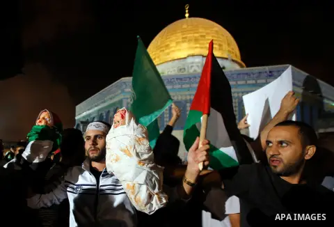 Palestinians hold a doll wrapped in a white cloth with red stains and shout slogans during a protest in front of the Dome of the Rock at the Al-Aqsa Mosque compound in the Old City of Jerusalem on July 20, 2014, in prote...