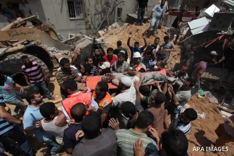 Palestinian rescue workers and civilians remove a lifeless body from the rubble of a house was destroyed by an Israeli missile strike, in Gaza City, Monday, July 21, 2014. On Sunday, the first major ground battle in two...