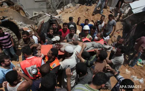 Palestinian rescue workers and civilians remove a lifeless body from the rubble of a house was destroyed by an Israeli missile strike, in Gaza City, Monday, July 21, 2014. On Sunday, the first major ground battle in two...