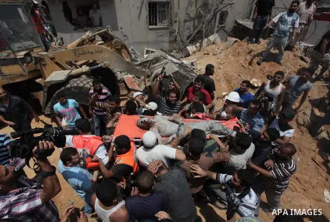 Palestinian rescue workers and civilians remove a lifeless body from the rubble of a house was destroyed by an Israeli missile strike, in Gaza City, Monday, July 21, 2014. On Sunday, the first major ground battle in two...