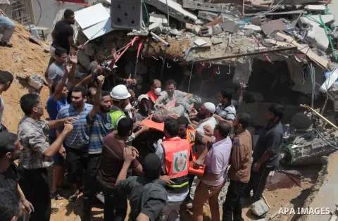 Palestinian rescue workers and civilians remove a lifeless body from the rubble of a house was destroyed by an Israeli missile strike, in Gaza City, Monday, July 21, 2014. On Sunday, the first major ground battle in two...