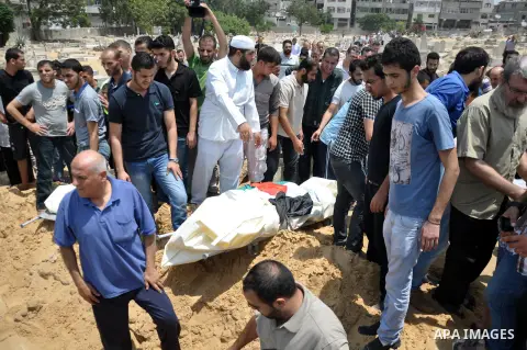 Mourners bury the bodies of Palestinian from al-Halaq family, who medics said were killed in an Israeli air strike on Sunday along with seven members from the same family during heavy Israeli shelling, at a cemetery in G...