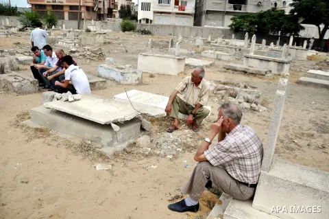 Relatives mourn on the bodies of Palestinian from al-Halaq family, who medics said were killed in an Israeli air strike on Sunday along with seven members from the same family during heavy Israeli shelling, at a cemetery...