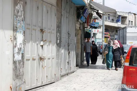 Palestinians walk past closed shops at a market in Jerusalem old city on 21 July 2014. Shops were shut in the West Bank cites and Jerusalem in solidarity with the at least 60 Palestinians who were killed in the neighbour...