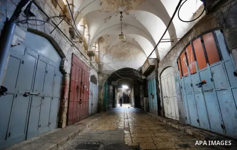Palestinians walk past closed shops at a market in Jerusalem old city on 21 July 2014. Shops were shut in the West Bank cites and Jerusalem in solidarity with the at least 60 Palestinians who were killed in the neighbour...