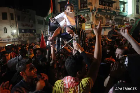 A Palestinian girl, who medics said wounded in an Israeli air strike on her family's house in Gaza Strip, holds a placard during a demonstration against Israel's military action and violence in the Gaza strip, in the Wes...