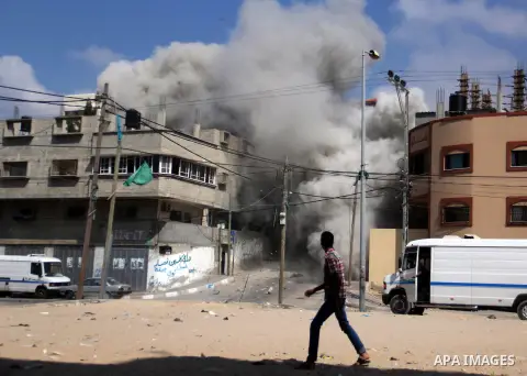 A Palestinian man walks as smoke rises from a destroyed building following an Israeli air strike at al-Shatee refugee camp, in Gaza City on July 21, 2014. The Palestinian death toll in an Israeli offensive in the Gaza St...