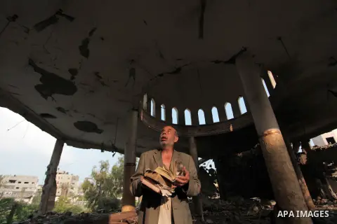 A Palestinian man holds copies of the Koran, Islam's holy book, as he inspects the rubble of a destroyed mosque following an overnight Israeli military strike on July 22, 2014 in Gaza City. UN chief Ban Ki-moon and US Se...