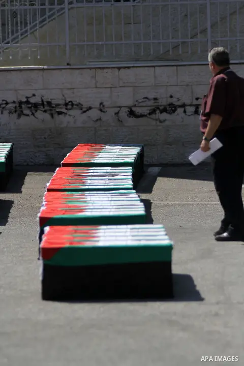 A Palestinian man stands near symbolic coffins during a protest in solidarity with Palestinians killed by Israeli forces in Gaza Strip, in the West Bank City of Ramallah on July 22, 2014. A series of Israeli air strikes...