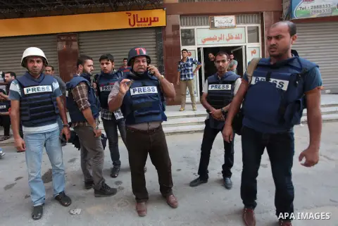 Palestinian journalists and reporters, who work in al-Jazeera Qatari television channel, stand outside their offices in Gaza City on July 22, 2014. Al Jazeera staffers evacuated their newsroom in Gaza City on Tuesday, sa...