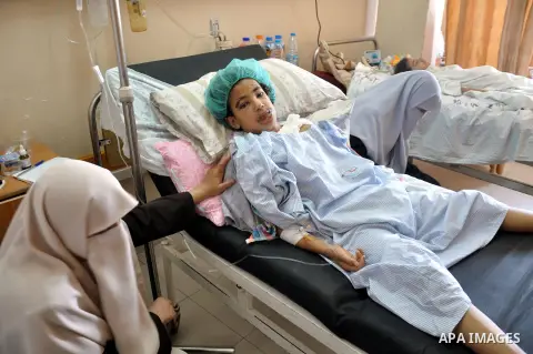 A Palestinian woman sits near her son, who medics said was wounded in an Israeli air strike, as he receives treatment at al-Shifa hospital in Gaza City on July 22, 2014. The Israeli operation in the Gaza Strip is enterin...