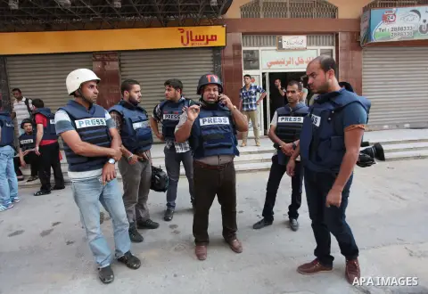 Palestinian journalists and reporters, who work in al-Jazeera Qatari television channel, stand outside their offices in Gaza City on July 22, 2014. Al Jazeera staffers evacuated their newsroom in Gaza City on Tuesday, sa...
