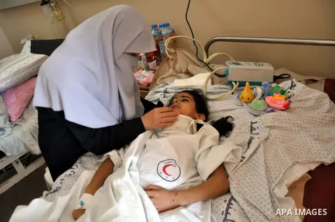 A Palestinian woman sits near her daughter, who medics said was wounded in an Israeli air strike, as she receives treatment at al-Shifa hospital in Gaza City on July 22, 2014. The Israeli operation in the Gaza Strip is e...