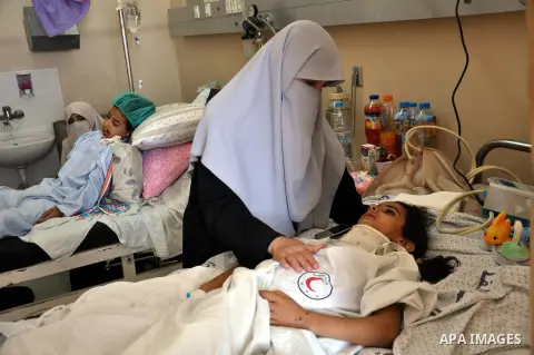 A Palestinian woman sits near her daughter, who medics said was wounded in an Israeli air strike, as she receives treatment at al-Shifa hospital in Gaza City on July 22, 2014. The Israeli operation in the Gaza Strip is e...