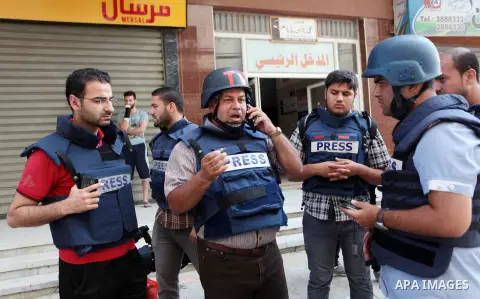 Palestinian journalists and reporters, who work in al-Jazeera Qatari television channel, stand outside their offices in Gaza City on July 22, 2014. Al Jazeera staffers evacuated their newsroom in Gaza City on Tuesday, sa...