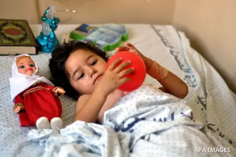 A Palestinian girl, who medics said was wounded in an Israeli air strike, plays as she eceives treatment at al-Shifa hospital in Gaza City on July 22, 2014. The Israeli operation in the Gaza Strip is entering the third w...