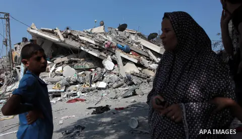 A Palestinian woman stands in front of the rubble of a residential building, which police said was destroyed in an Israeli air strike, in Gaza City July 22, 2014. Israel kept up its assaults in the Gaza Strip on Tuesday,...