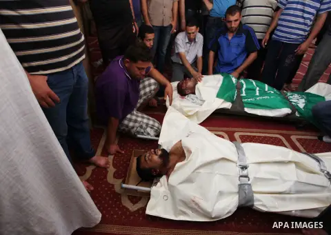 Relatives gather around the lifeless bodies of Palestinian cousins Adnan Habib, 22, foreground, and Mahmoud Habib, 27, killed in separate incidents earlier Wednesday, on the sixteenth day of the war in Gaza, during their...