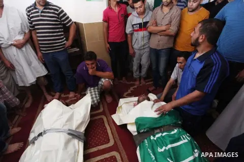 Relatives gather around the lifeless bodies of Palestinian cousins Adnan Habib, 22, foreground, and Mahmoud Habib, 27, killed in separate incidents earlier Wednesday, on the sixteenth day of the war in Gaza, during their...
