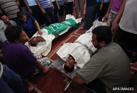 Relatives gather around the lifeless bodies of Palestinian cousins Adnan Habib, 22, foreground, and Mahmoud Habib, 27, killed in separate incidents earlier Wednesday, on the sixteenth day of the war in Gaza, during their...