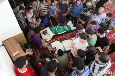 Relatives gather around the lifeless bodies of Palestinian cousins Adnan Habib, 22, foreground, and Mahmoud Habib, 27, killed in separate incidents earlier Wednesday, on the sixteenth day of the war in Gaza, during their...