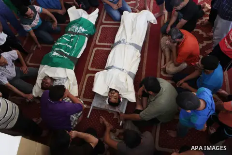 Relatives gather around the lifeless bodies of Palestinian cousins Adnan Habib, 22, foreground, and Mahmoud Habib, 27, killed in separate incidents earlier Wednesday, on the sixteenth day of the war in Gaza, during their...