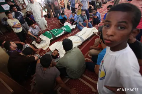 Relatives gather around the lifeless bodies of Palestinian cousins Adnan Habib, 22, foreground, and Mahmoud Habib, 27, killed in separate incidents earlier Wednesday, on the sixteenth day of the war in Gaza, during their...