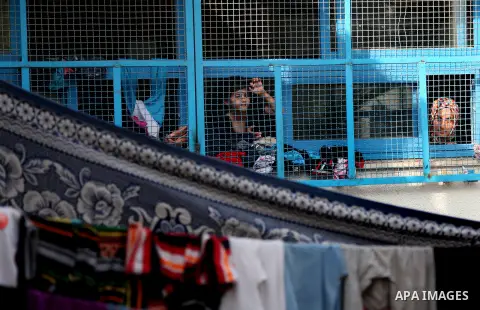 Displaced Palestinian children from Beit Hanun in the northern Gaza Strip stand behind the window of a classroom on July 23, 2014 at a UN school in the refugee camp of Jabalia where displaced families have taken refuge a...