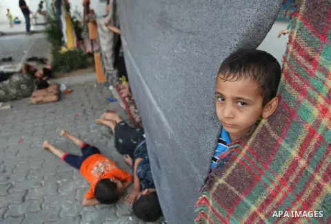 A displaced Palestinian boy stands behidn blankets serving as a separation curtain for his family on July 23, 2014 at a UN school in the northern Gaza Strip refugee camp of Jabalia where displaced families have taken ref...