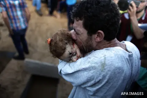 A relative of two-year old Palestinian Salma Radiya who was killed by shrapnel from an Israeli tank shell in the north of the Gaza Strip holds her body at a cemetery in Beit Lahia on July 23, 2014. A series of strikes an...