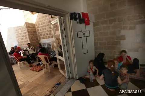 Displaced Palestinian women and children sit in a Greek Orthodox church where many Palestinians are taking shelter in Gaza City on July 23, 2014. For the first time in years, Gaza City's Greek Orthodox church is packed t...