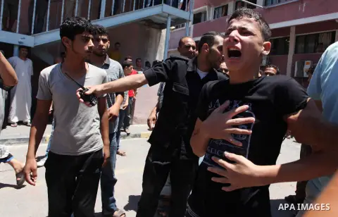 Palestinians react as they sit at Nasser hospital in Khan Younis, in the southern Gaza Strip, after one of thier relatives was killed by an Israeli army shelling on July 24, 2014. Photo by Ashraf Amra